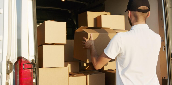 A man arranging packed carton boxes inside a truck.